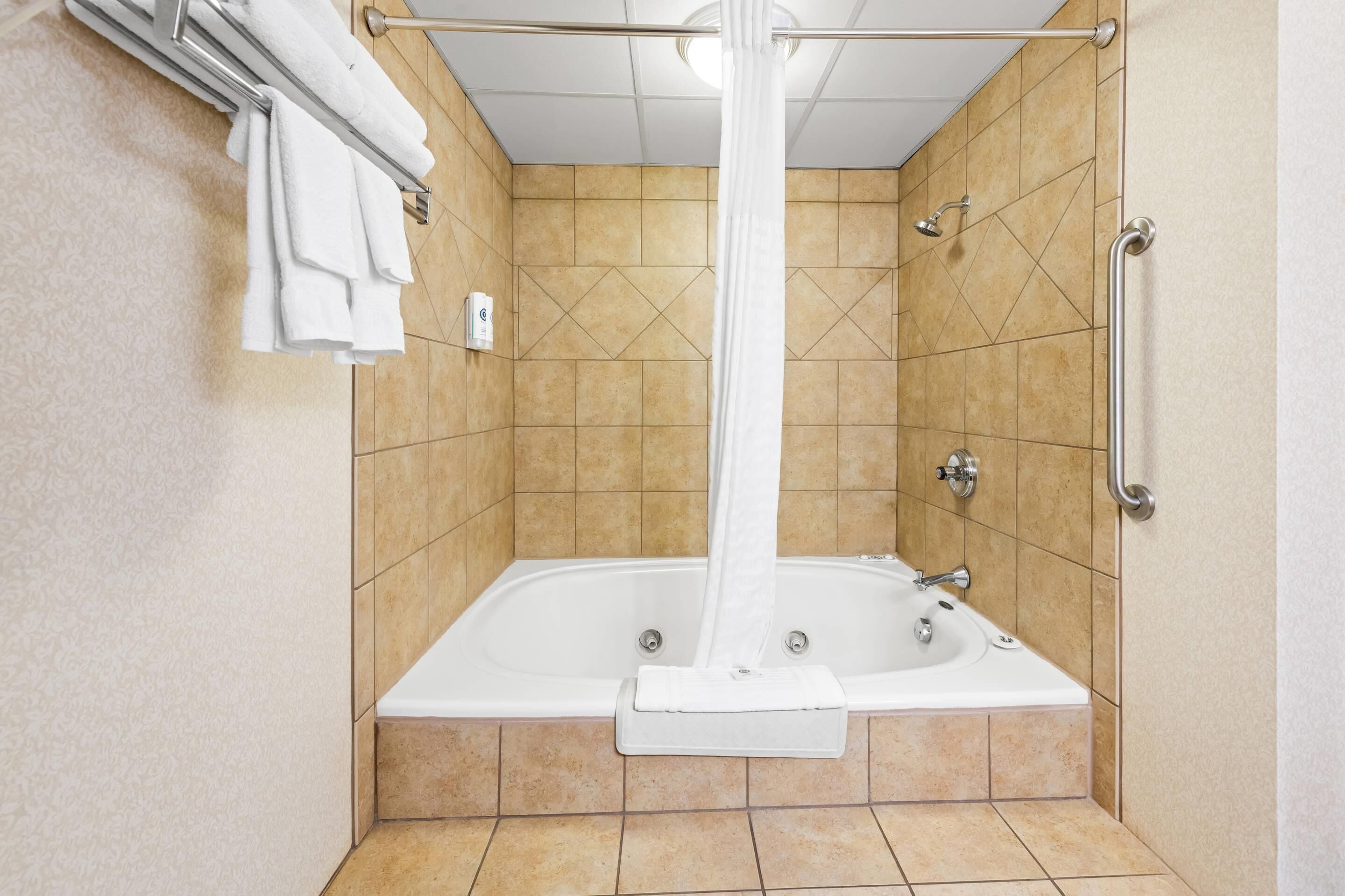 Ein modernes Badezimmer mit einer Eckbadewanne, einem Handtuchhalter und einer Duschbrause.
