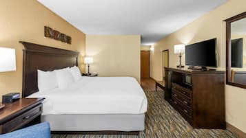 Una habitación de hotel con una cama grande, mesitas de noche, televisión y un escritorio con silla.