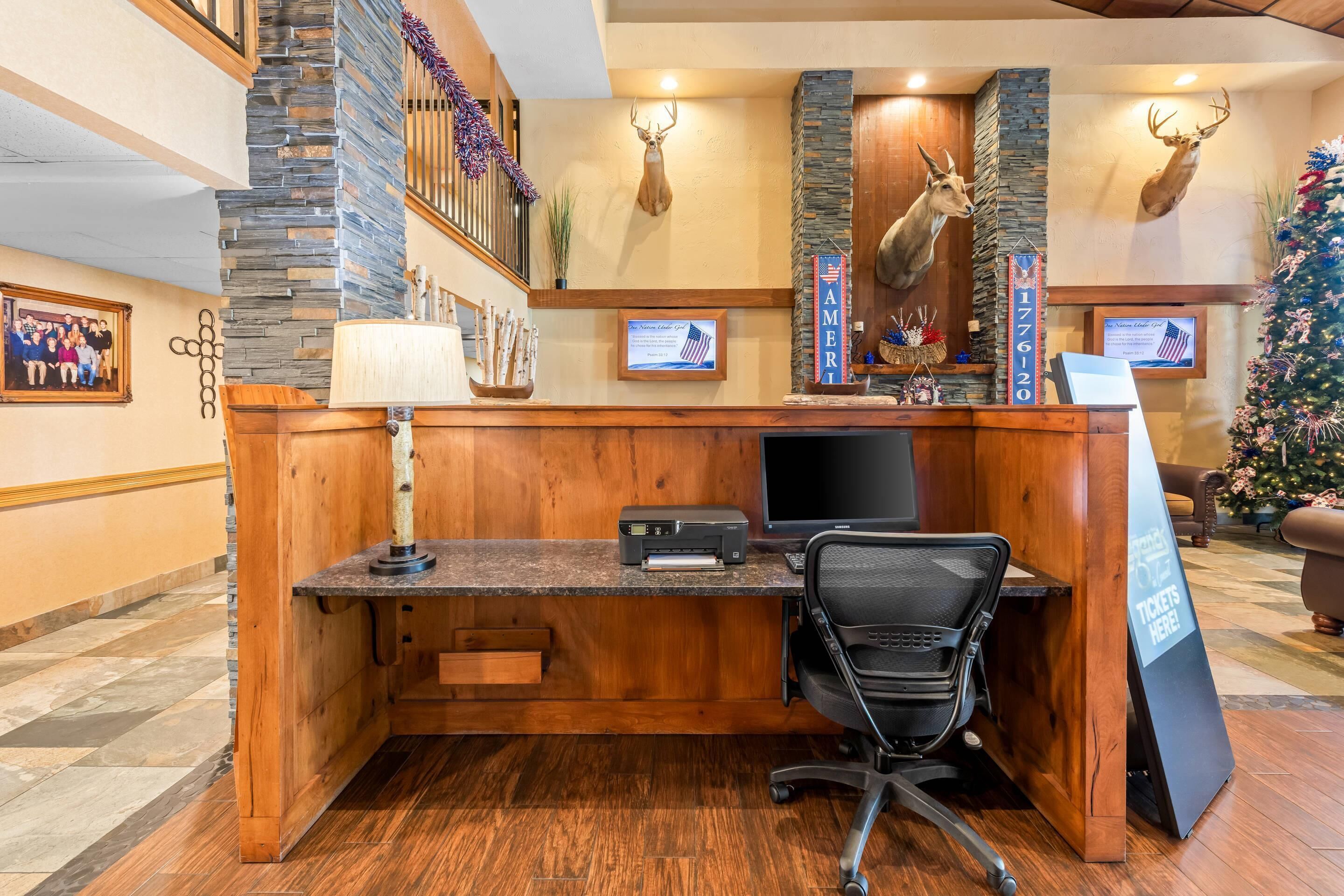 A reception desk with a computer, printer, and office chair.