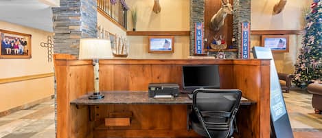 A reception desk with a computer, printer, and office chair.