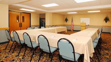 A conference room with long tables and chairs, carpeted floor, and a whiteboard.