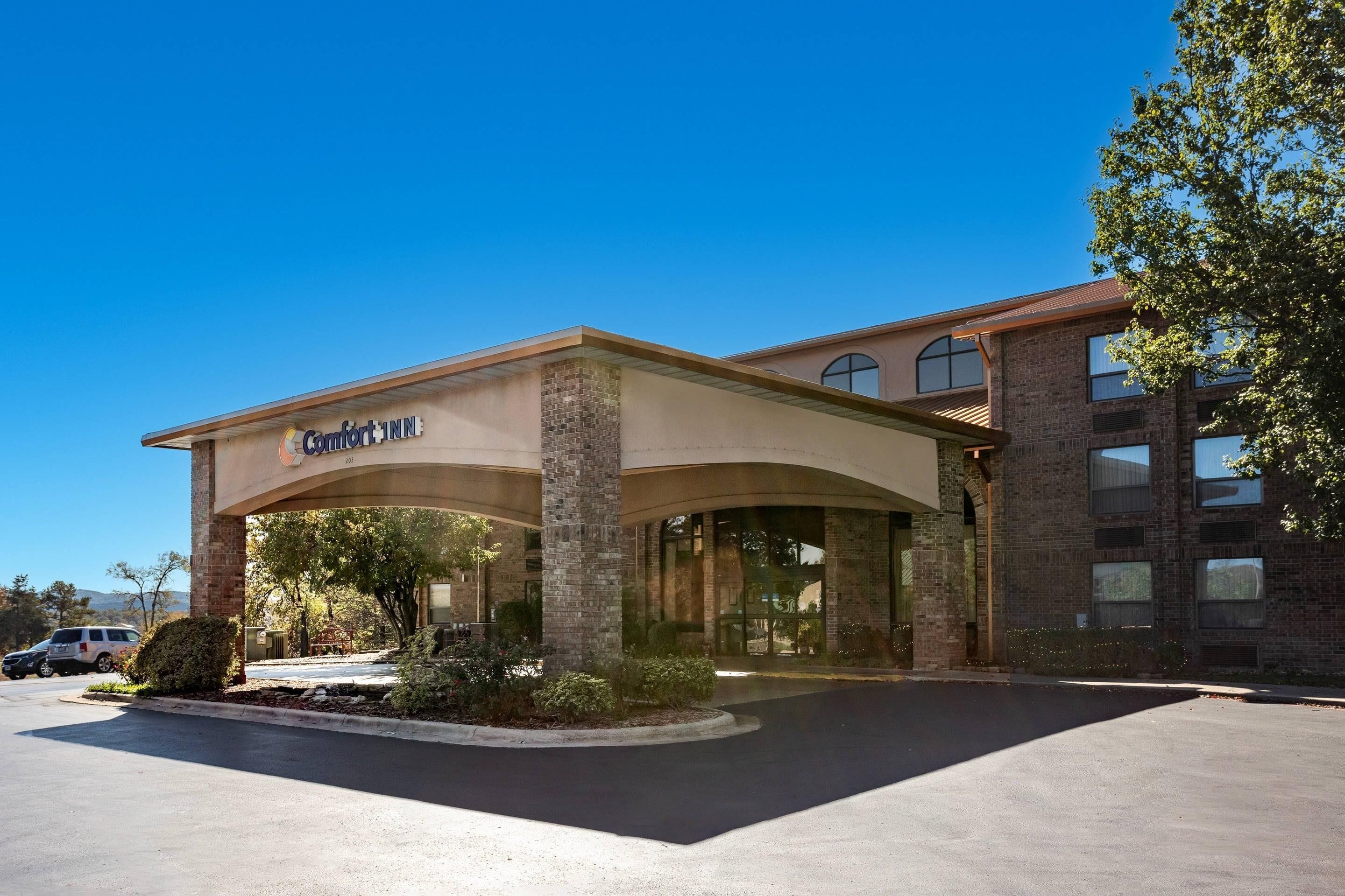 Entrada de un hotel con un letrero que dice 'Comfort Inn' y un estacionamiento al frente.