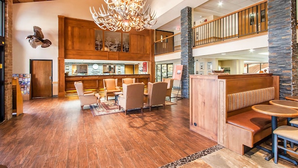 A spacious lobby with wooden flooring, a central seating area, a reception desk, and a decorative chandelier. - Comfort Inn at Thousand Hills (Branson)