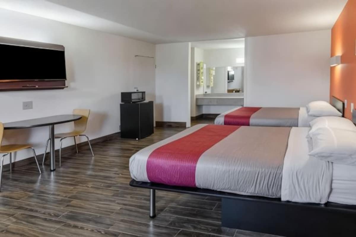 Une chambre d’hôtel avec deux lits, une télévision, un bureau et une chaise.