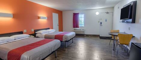 Hotelkamer met twee bedden, een bureau, een stoel, een televisie en een raam met gordijnen.