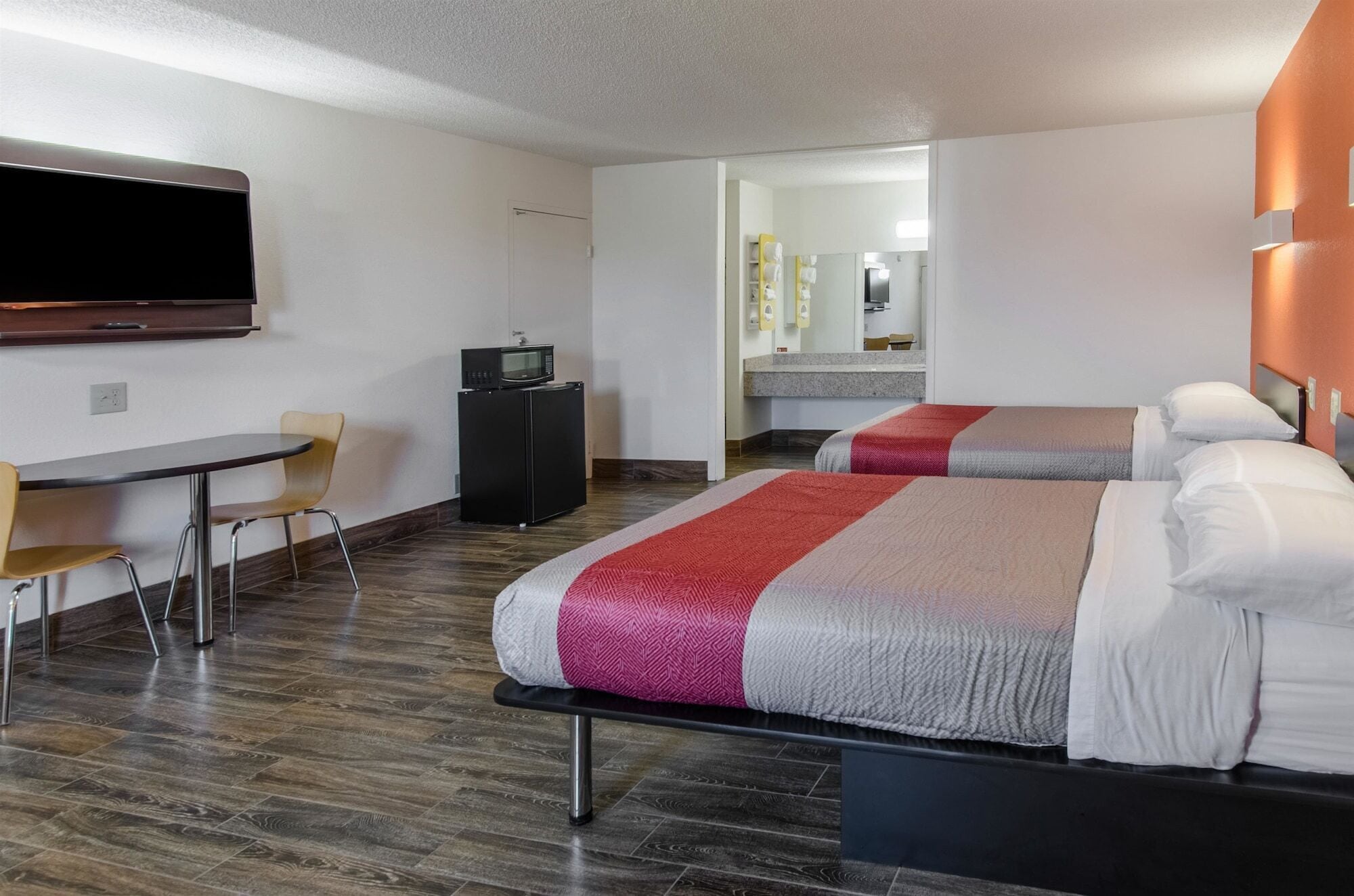 A hotel room with two beds, a TV, a desk, and a chair.