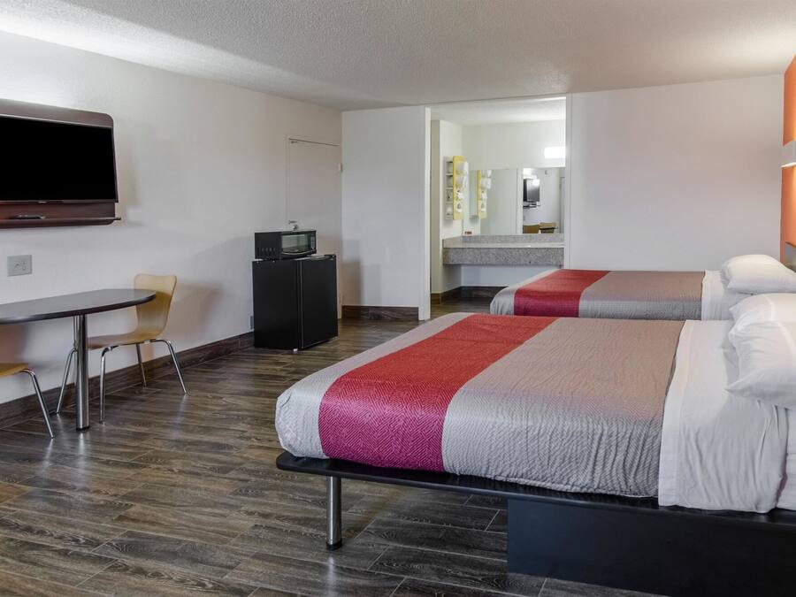 A hotel room with two beds, a TV, a desk, and a chair.