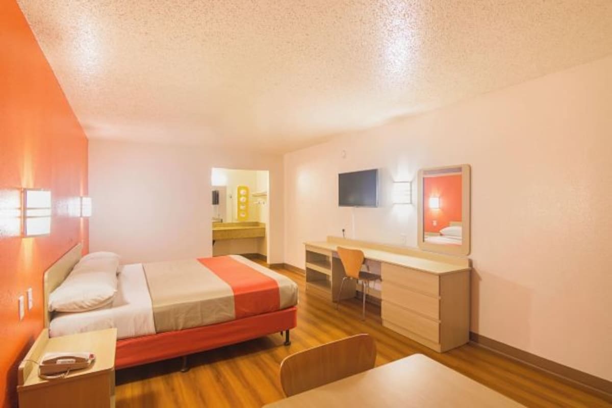 Une chambre d’hôtel équipée d’un lit, d’un bureau, d’une chaise, d’une télévision et d’un miroir.