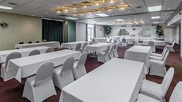 A conference room with multiple tables and chairs, a patterned carpet, and a chandelier.