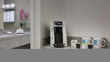 Een koffiezetapparaat, een wastafel en een handdoekhouder in een badkamer.