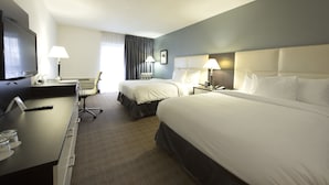 Une chambre d’hôtel avec deux lits, un bureau, une télévision et deux lampes.