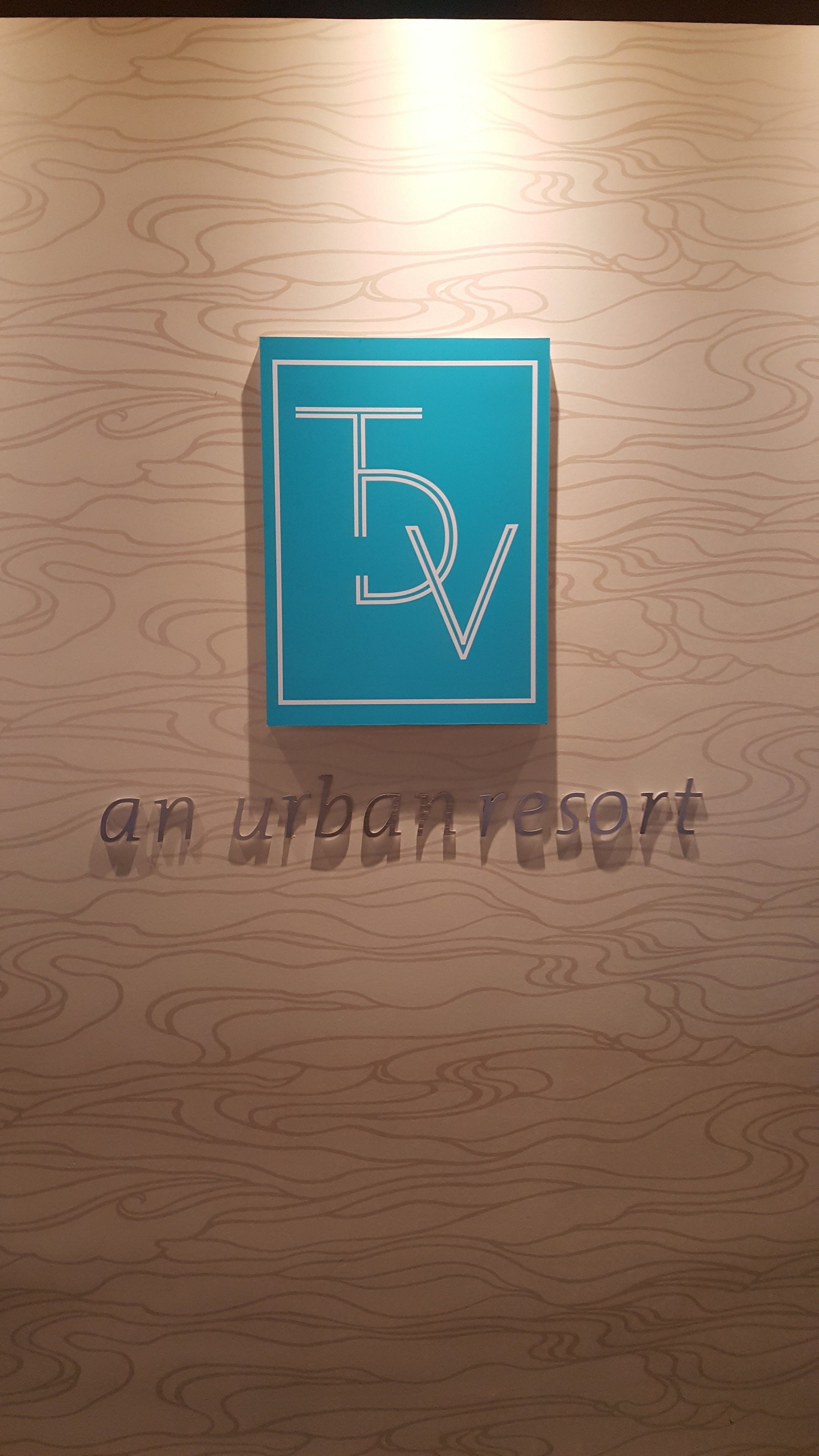 Un logo comprenant les lettres « TV » et les mots « un lieu de détente urbain », le tout sur un fond en bois.
