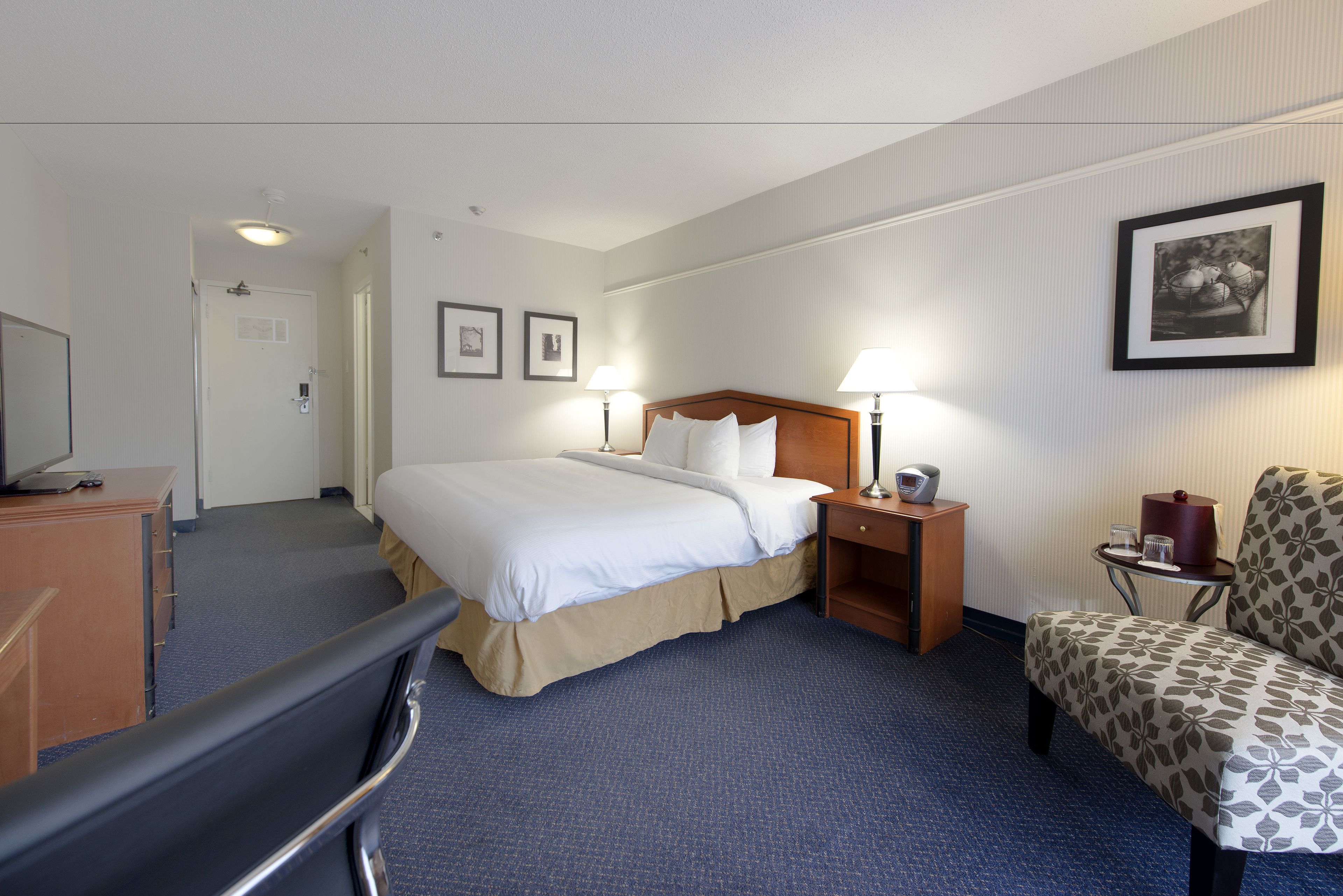 Een hotelkamer met een bed, nachtkastjes, een stoel, een bureau en een televisie.
