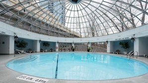 Une piscine intérieure dotée d’un toit en verre, d’un panneau indiquant une profondeur de 3 pieds et d’un avertissement interdisant de plonger.