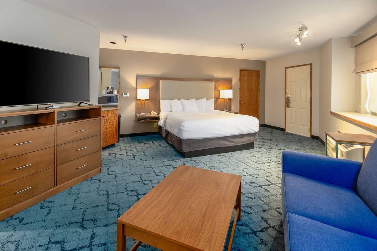 Ein Hotelzimmer mit einem großen Bett, einem Fernseher, einem Schreibtisch und einem blauen Sofa.
