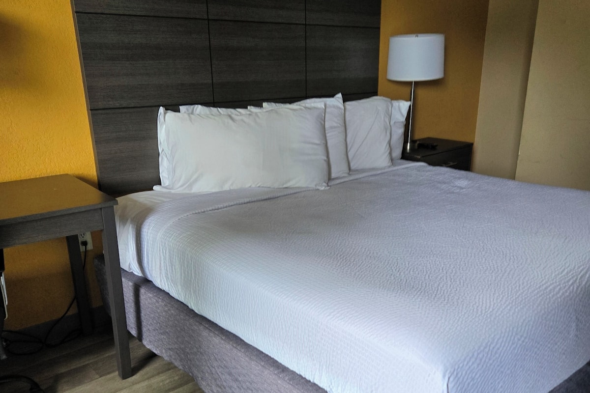 Une chambre d’hôtel avec un grand lit, une table de chevet, une lampe et un plancher en bois.