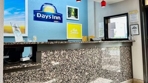A reception area with a Days Inn sign, framed pictures, and a counter with a granite top. - Days Inn by Wyndham Charlotte Northlake (Charlotte)