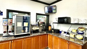 A kitchen with a microwave, coffee maker, and a TV mounted on the wall. - Days Inn by Wyndham Charlotte Northlake (Charlotte)