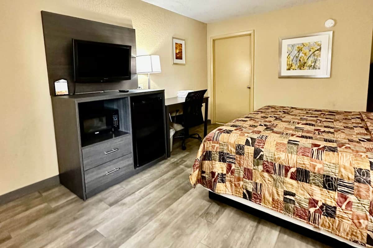 Une chambre d’hôtel avec un lit, un bureau, une télévision et une porte.