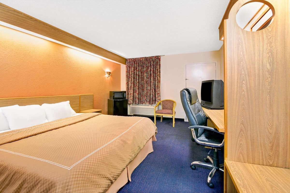 Une chambre d’hôtel comprenant un lit, un bureau avec une chaise, une télévision et une petite table.