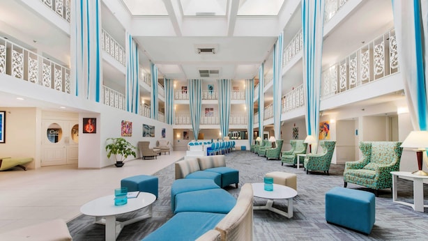 A spacious lobby with a high ceiling, multiple seating areas, and a central staircase.