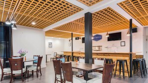 A modern dining area with wooden ceiling panels, a bar counter, and multiple seating arrangements.