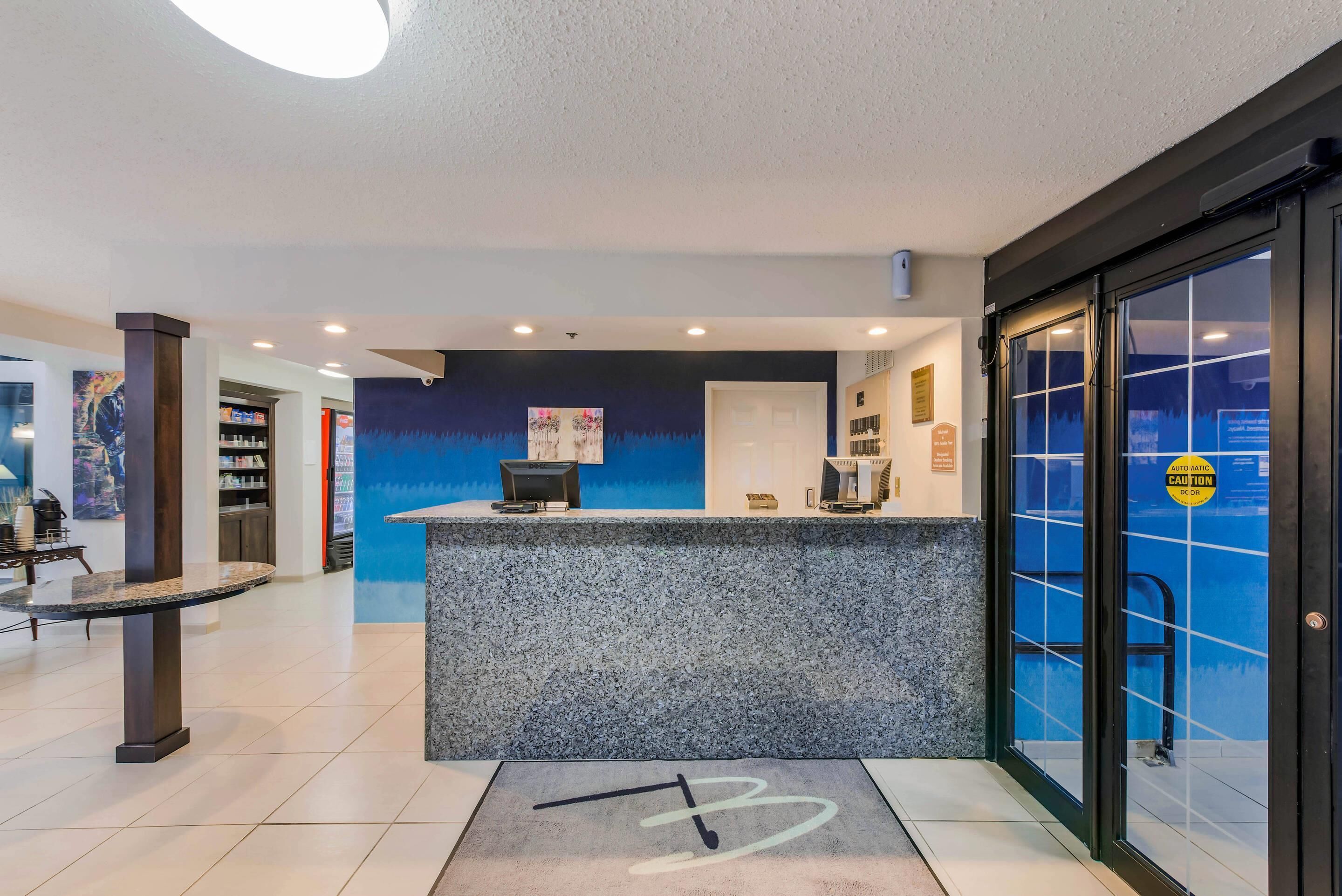 A reception area with a marble counter, a coffee machine, and a blue wall with a painting.