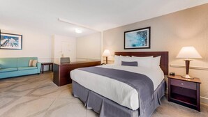 A hotel room with a large bed, a desk, a sofa, and two lamps.