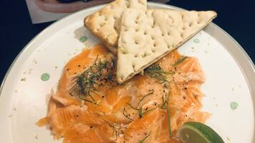 Une assiette de saumon fumé, servie avec des crackers et un quartier de citron vert.