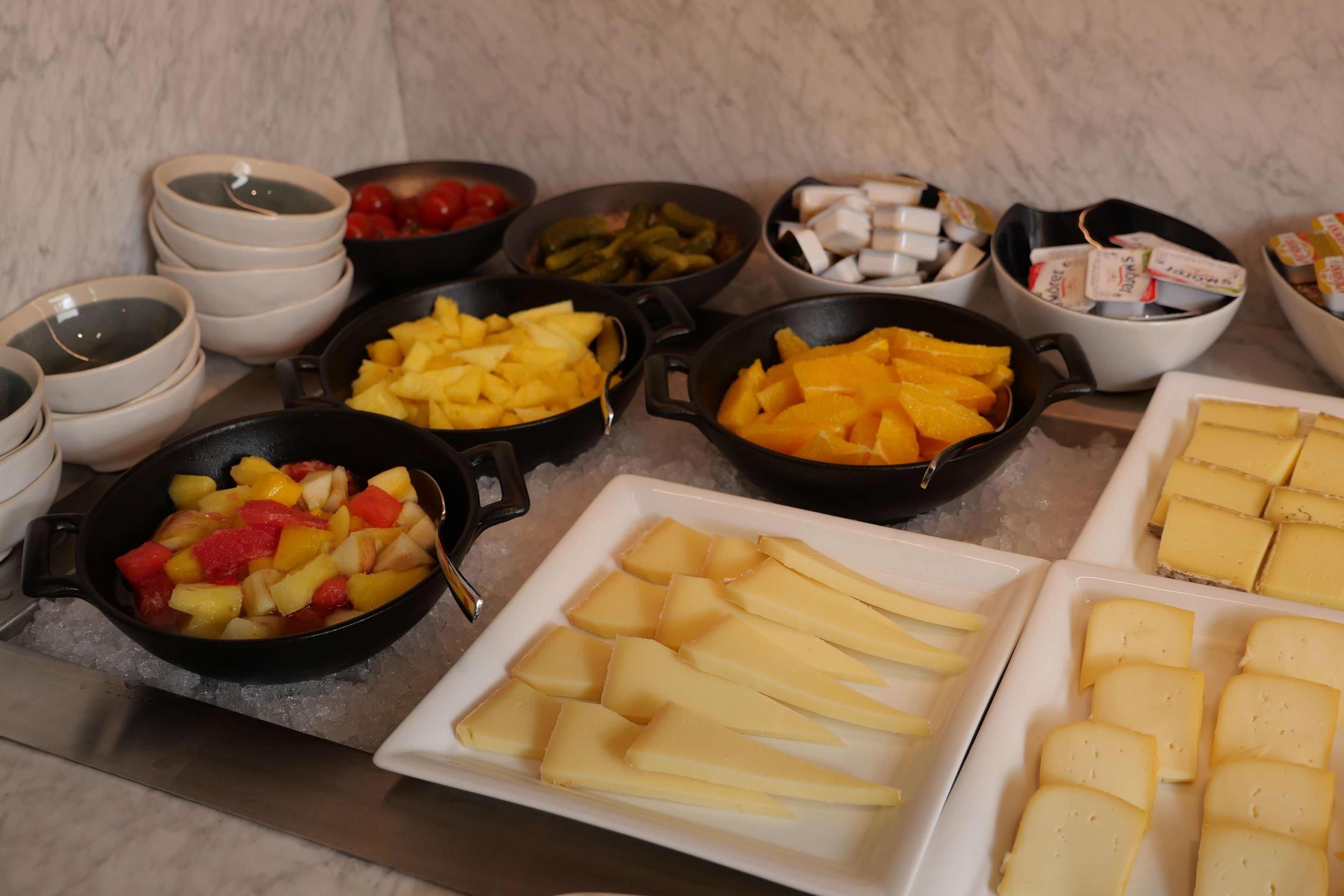 Un buffet con diversi cibi, tra cui frutta, formaggi e salse.