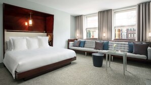 Una habitación de hotel con una cama grande, un sofá, una mesita y un cubo de basura.
