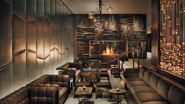Un salón moderno con sofás de cuero, mesas y chimenea.