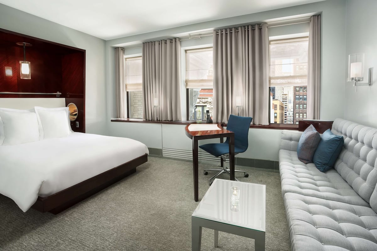 Quarto de hotel com cama, sofá, escrivaninha e cadeira.