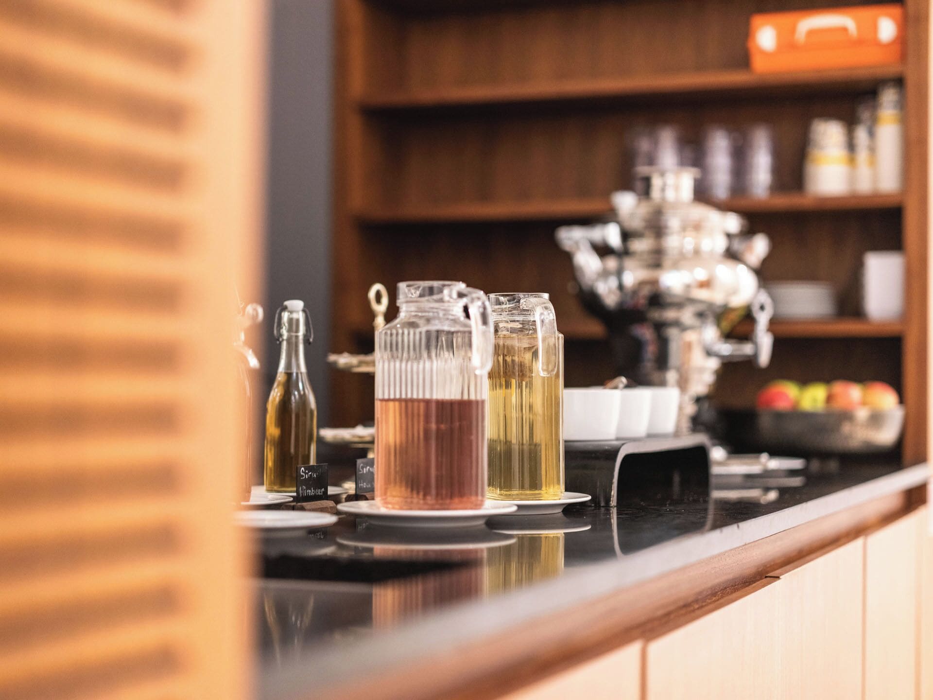 A bar area with a counter, a coffee machine, and various glassware and bottles.