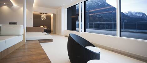 A modern interior with a large window, a sofa, a chair, and a small table.