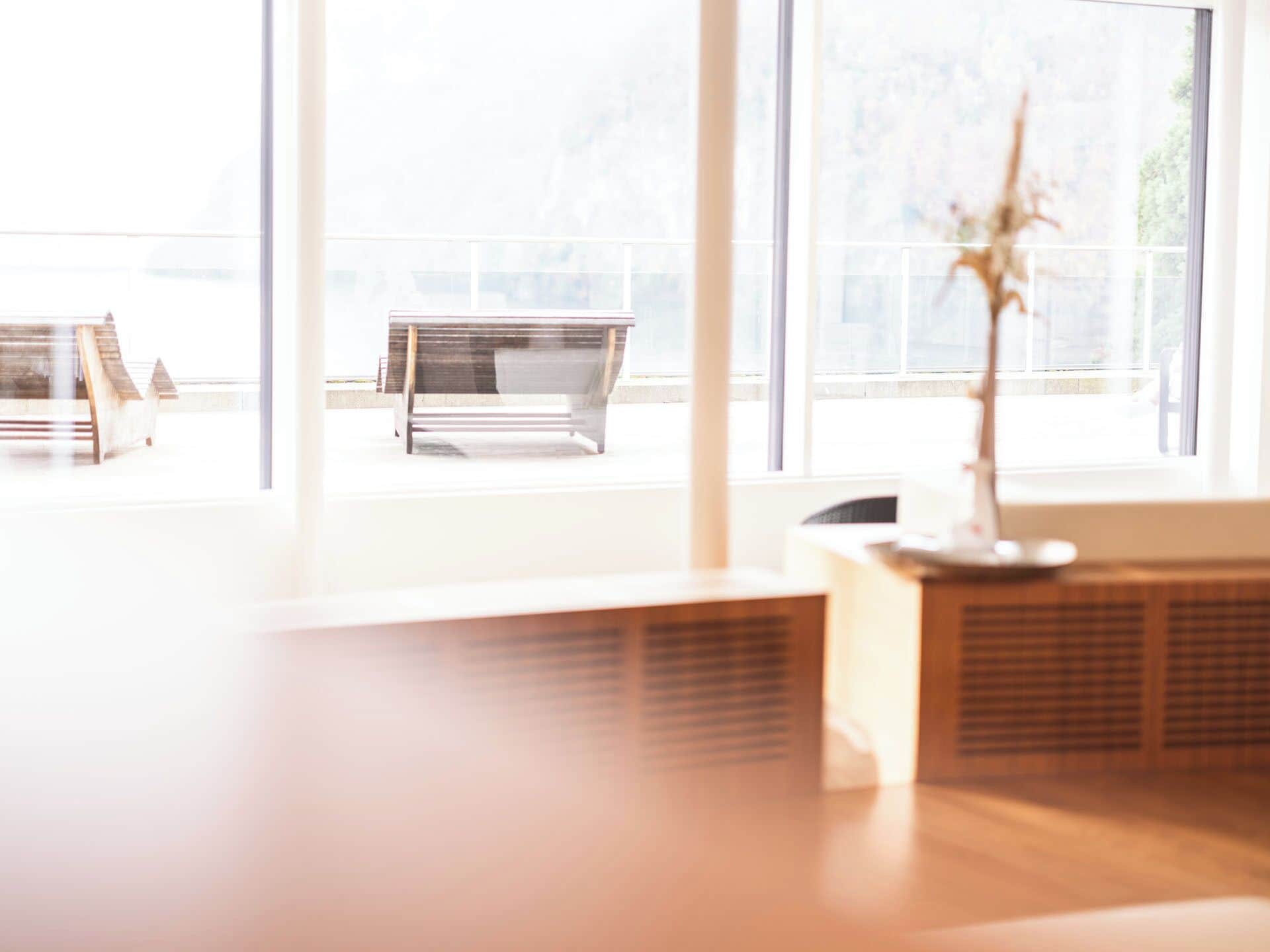 A room with large windows, a wooden bench, and a plant.