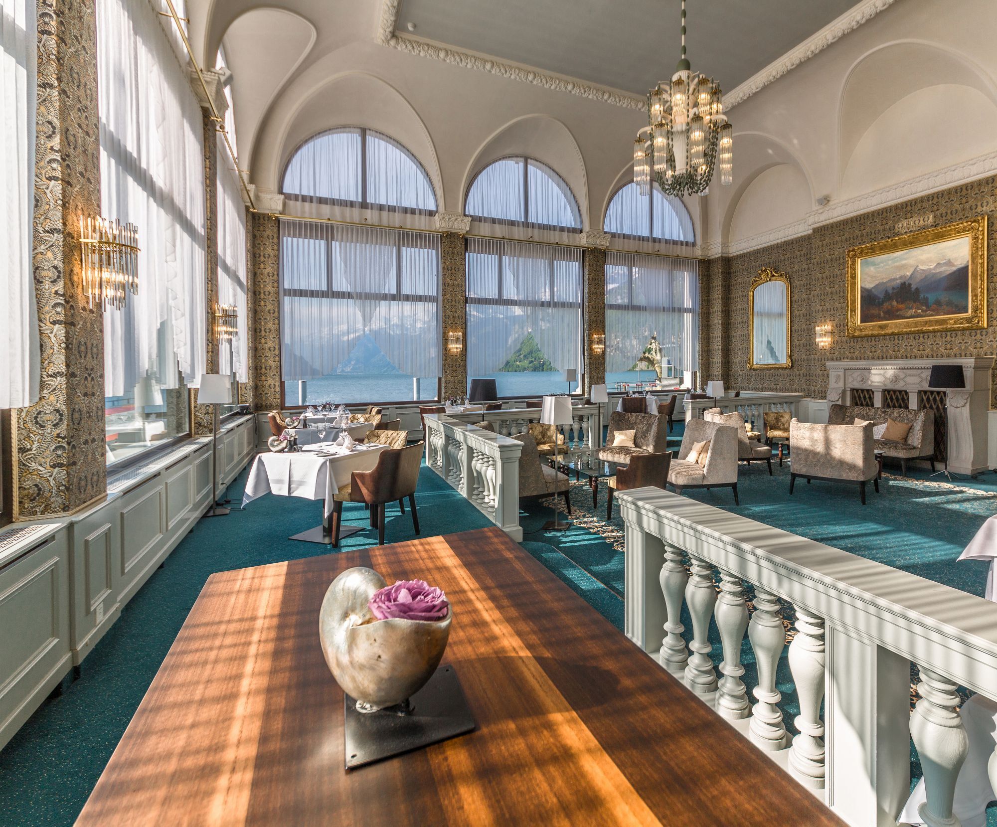 En rymlig hotellobby med en stor matsal, flera olika sittgrupper och utsikt över havet genom stora fönster.