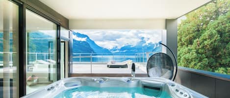 Un jacuzzi con vista a montañas y un balcón con una silla.