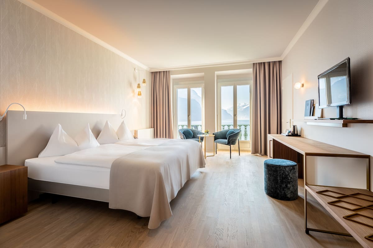 Une chambre d’hôtel avec un grand lit, un bureau, une télévision et une vue sur les montagnes.