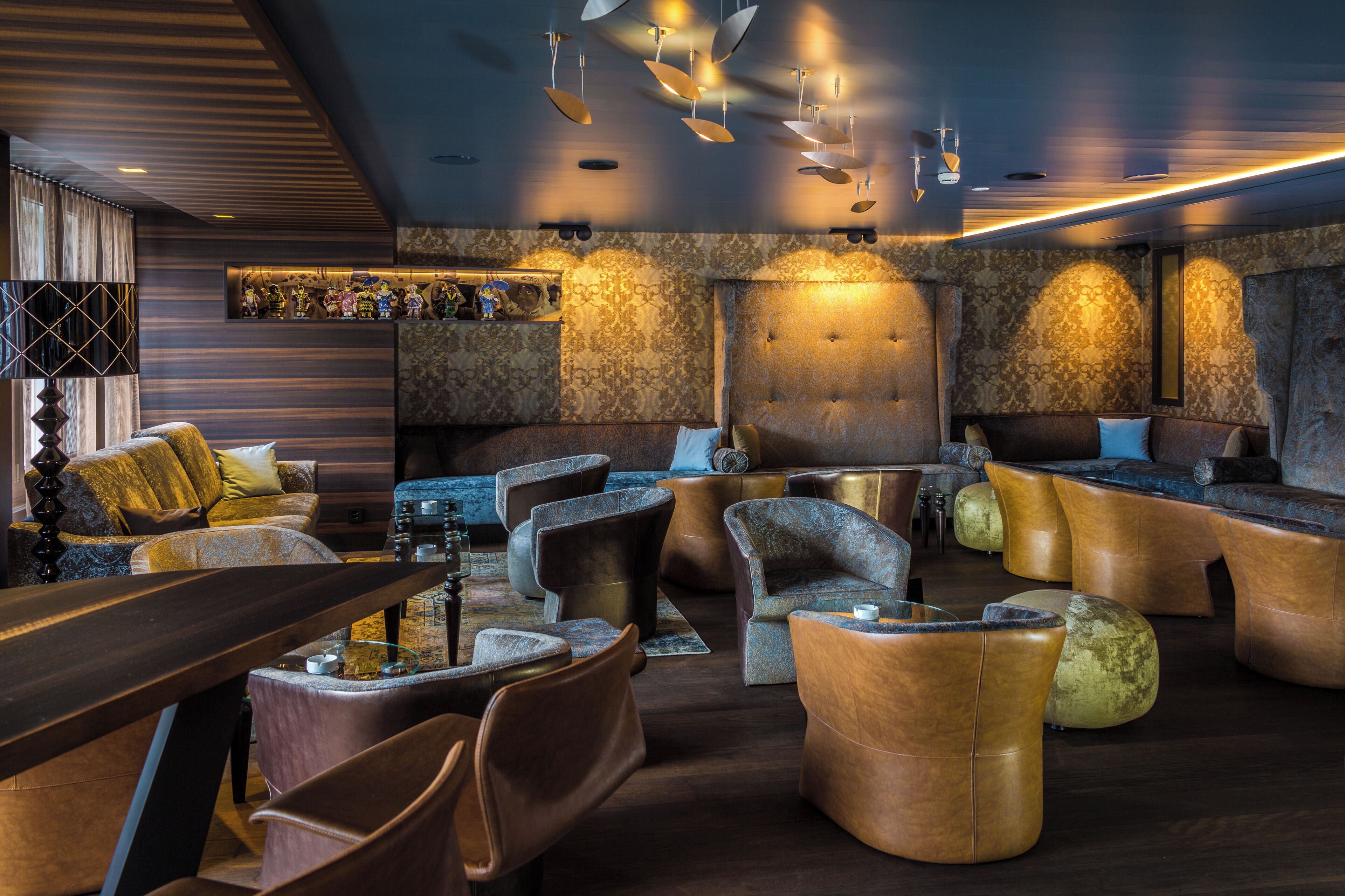 Ein stilvoller Lounge-Bereich mit Ledersofas, einer Bar und einer Wand mit Musterdesign.