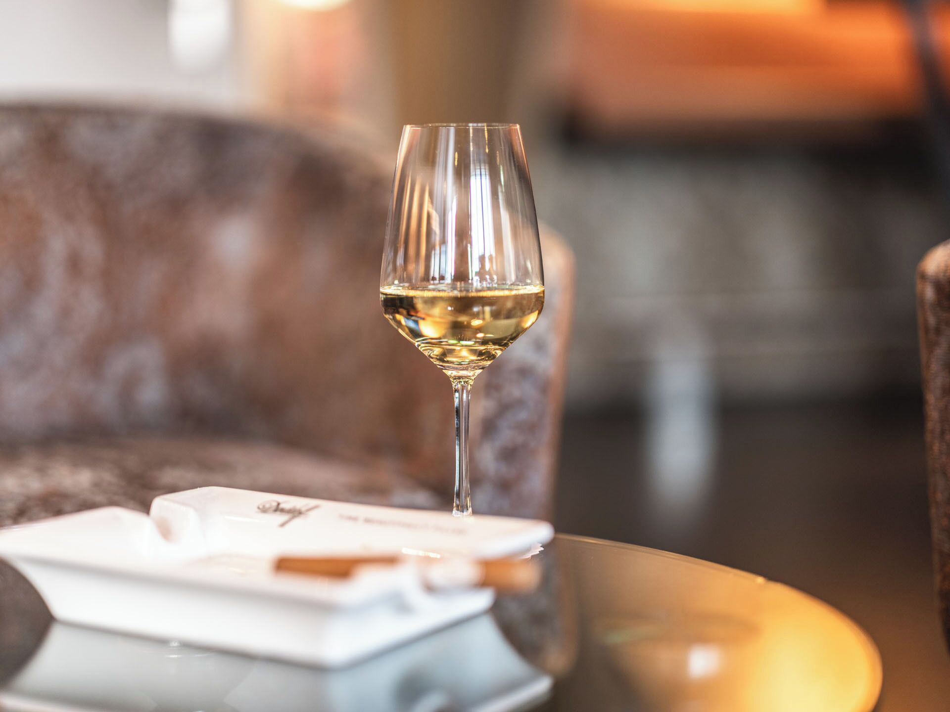 Een glas witte wijn op een tafel, met een menukaart en een servet.