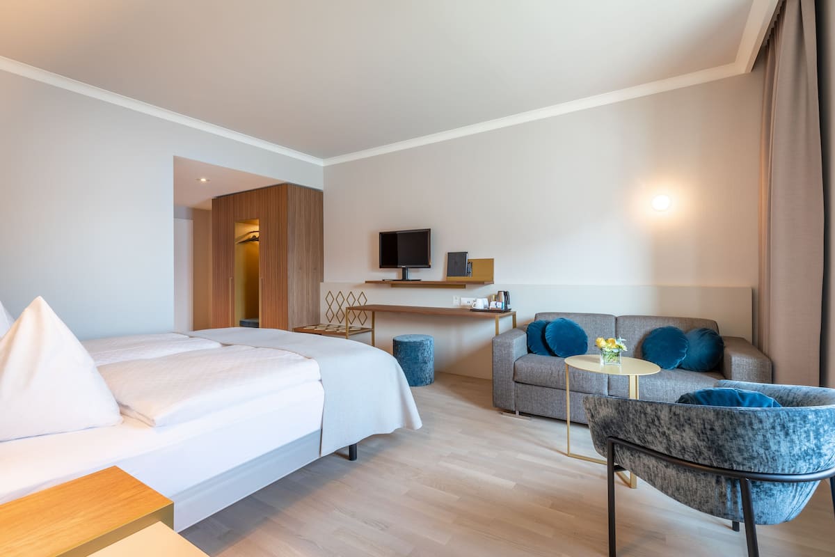 Une chambre d’hôtel moderne équipée d’un lit, d’un canapé, d’une petite table et d’un téléviseur.