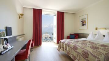 Ein Hotelzimmer mit Bett, Schreibtisch und Blick auf Berge durch das Fenster.