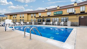 A hotel with a swimming pool, outdoor seating, and a clear blue sky. - Quality Inn & Suites Brownsburg - Indianapolis West (Brownsburg)