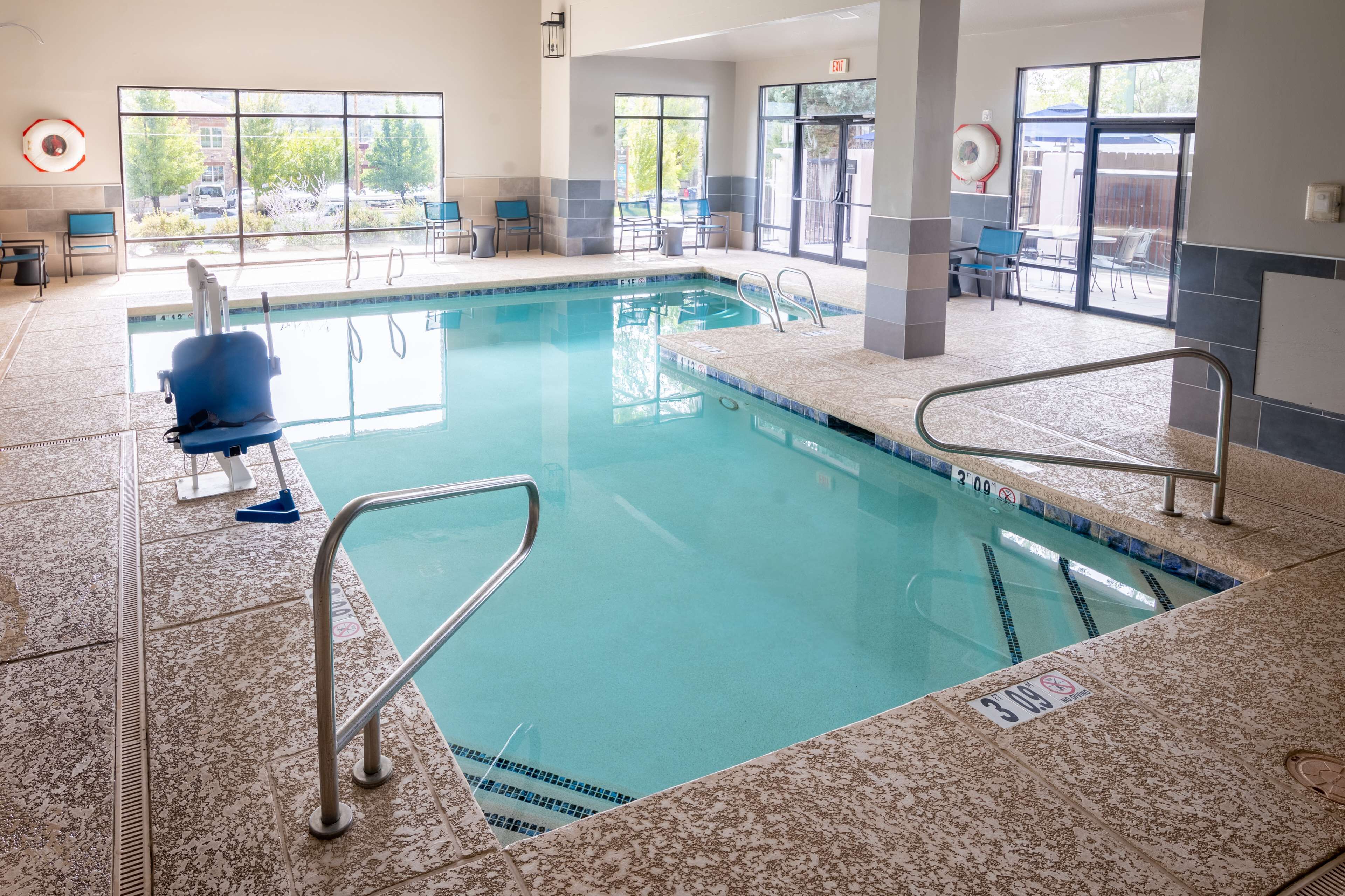 An indoor swimming pool with clear water, tiled walls, and a view of the outside.