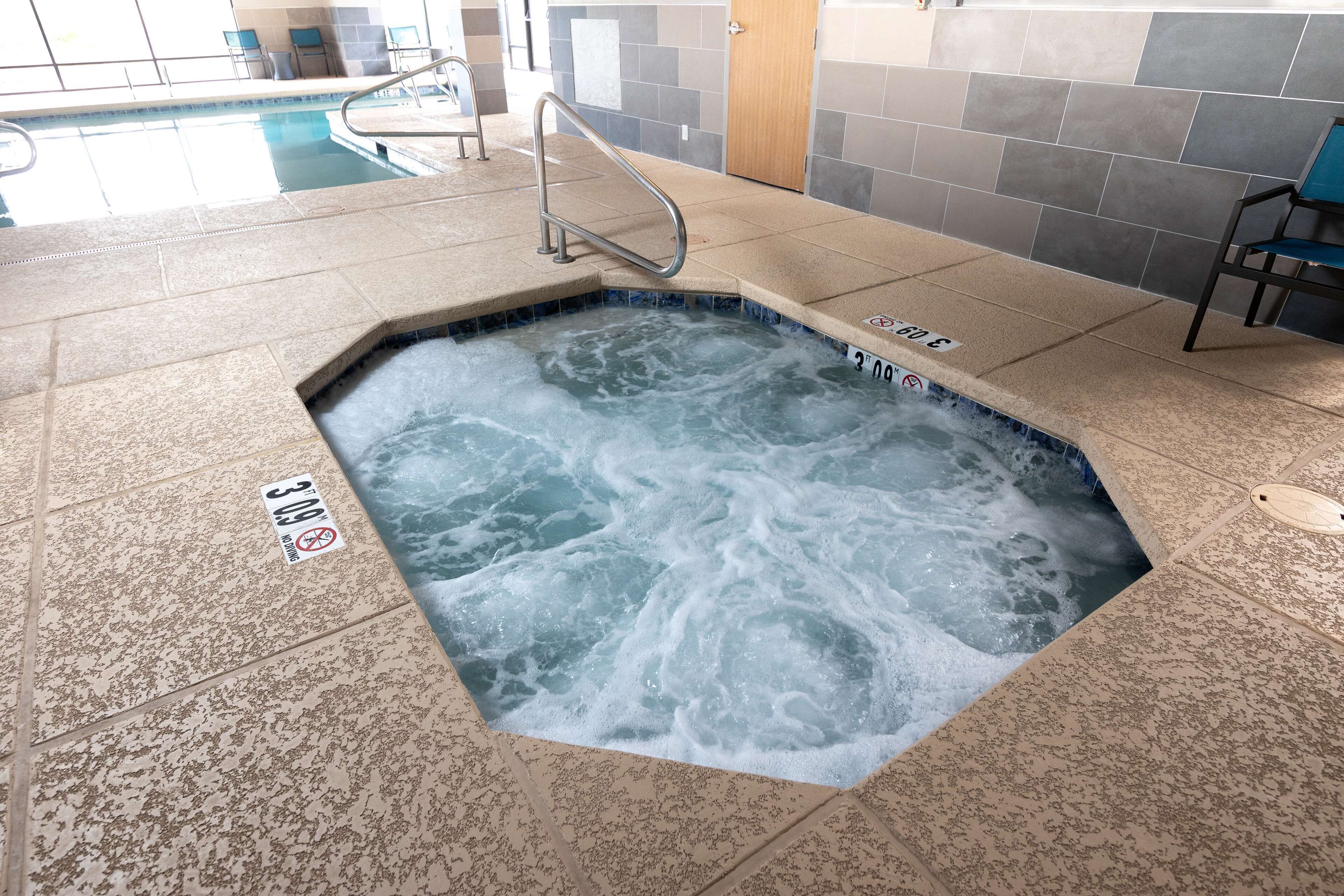 A hot tub with a metal railing, a tiled floor, and a sign indicating a 3'9" depth.
