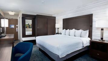 Een hotelkamer met een groot bed, een bureau, een stoel, een televisie en een kledingkast.