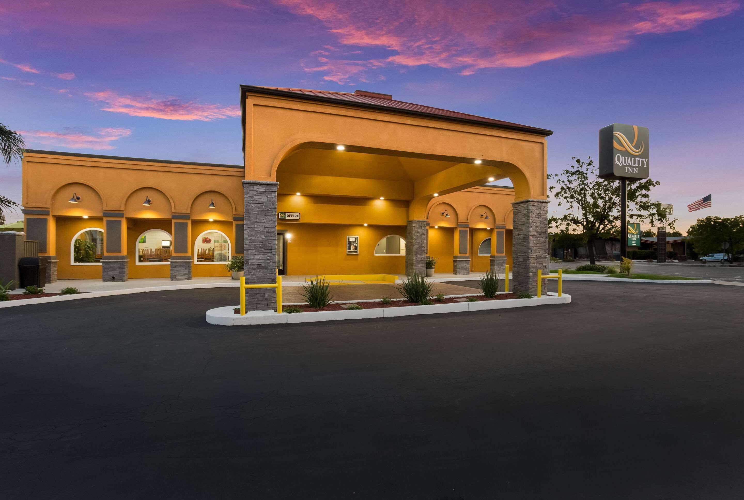 A hotel with a yellow facade, multiple arches, and a sign indicating it is a Quality Inn.