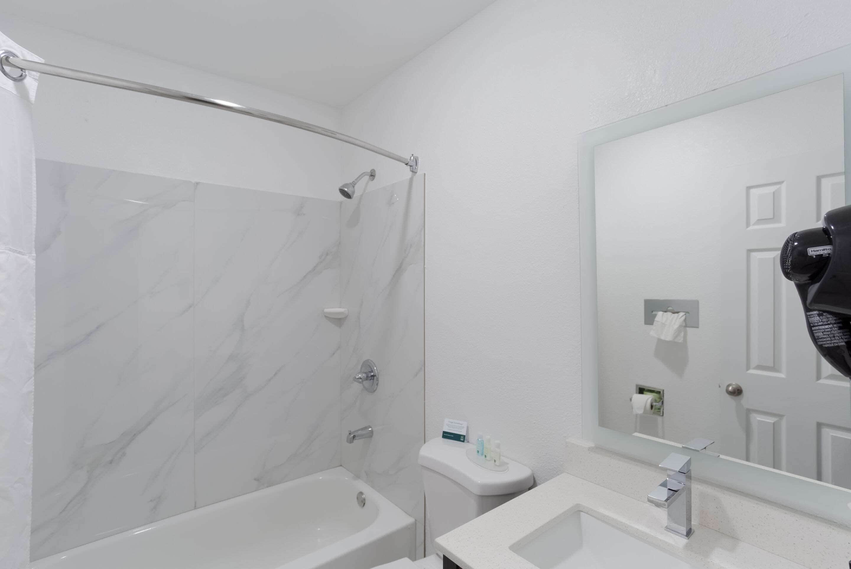 Een moderne badkamer met een douchecabine van glas, een wit toilet en een wastafel met spiegel.