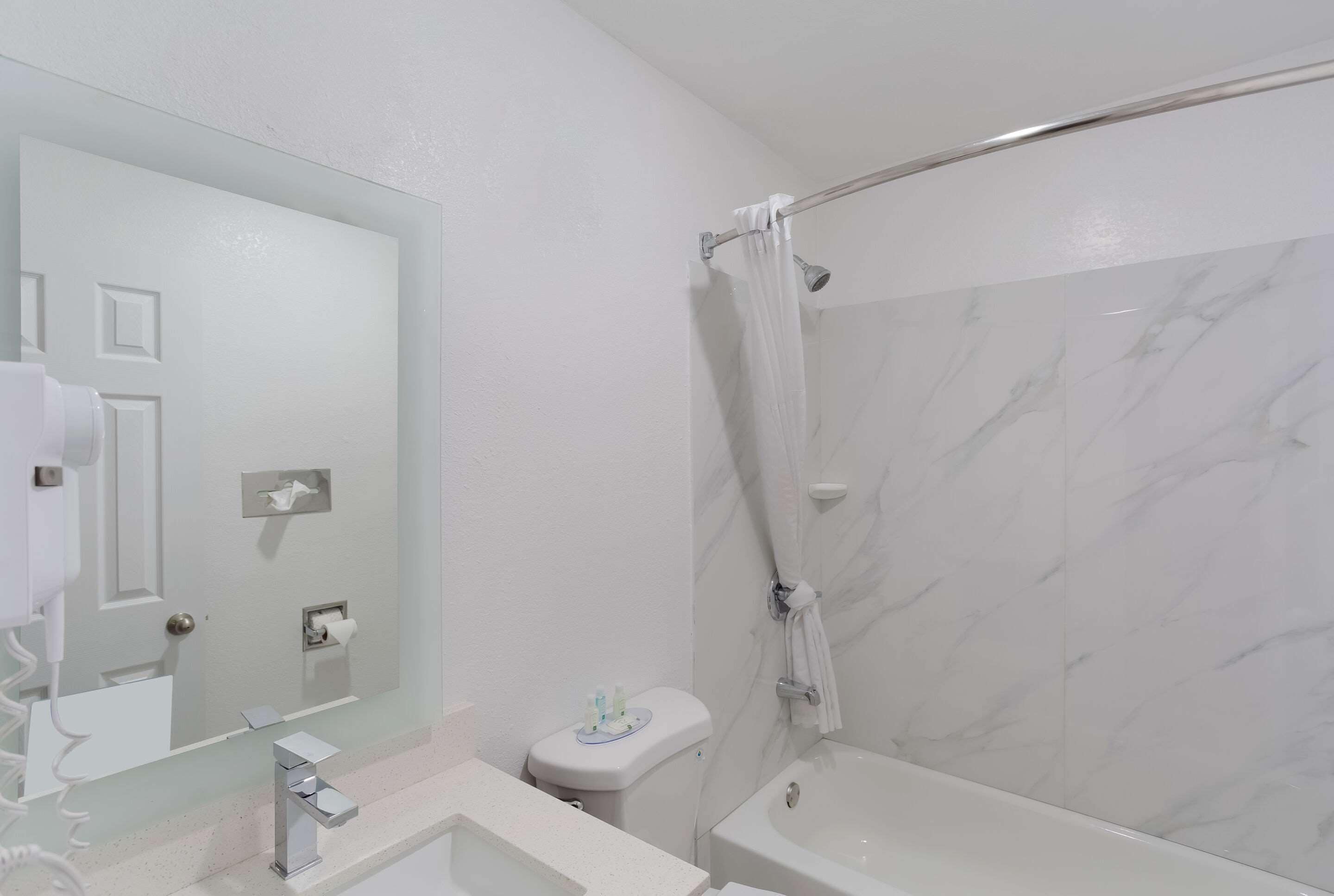 Un baño con lavamanos blanco, espejo y ducha.